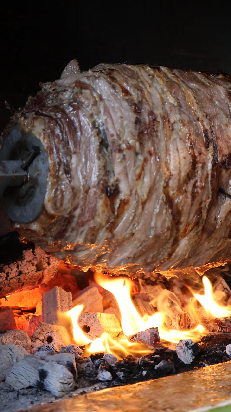 Cağ kebabı turning on a horizontal spit over a wood fire